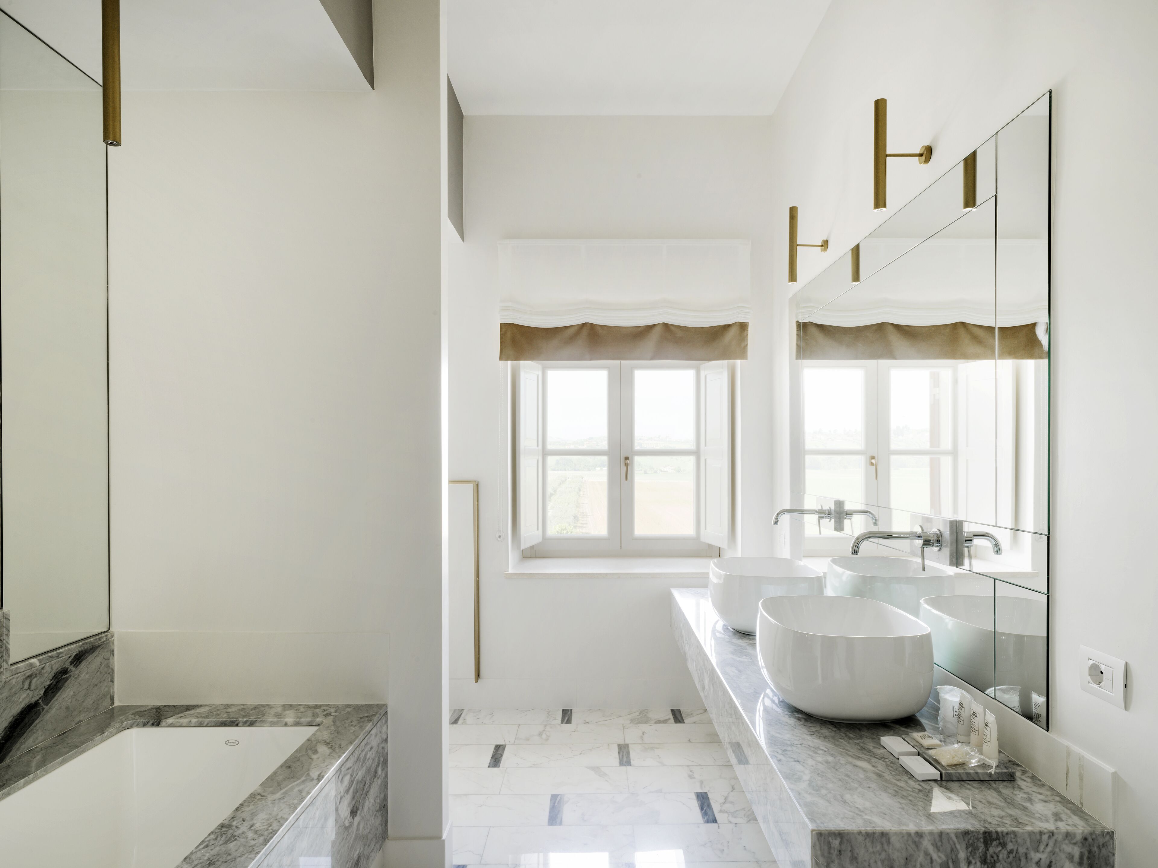 A modern bathroom with two sinks, a large mirror, and a bathtub.