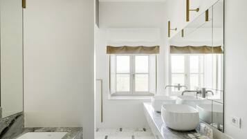 A modern bathroom with two sinks, a large mirror, and a bathtub.