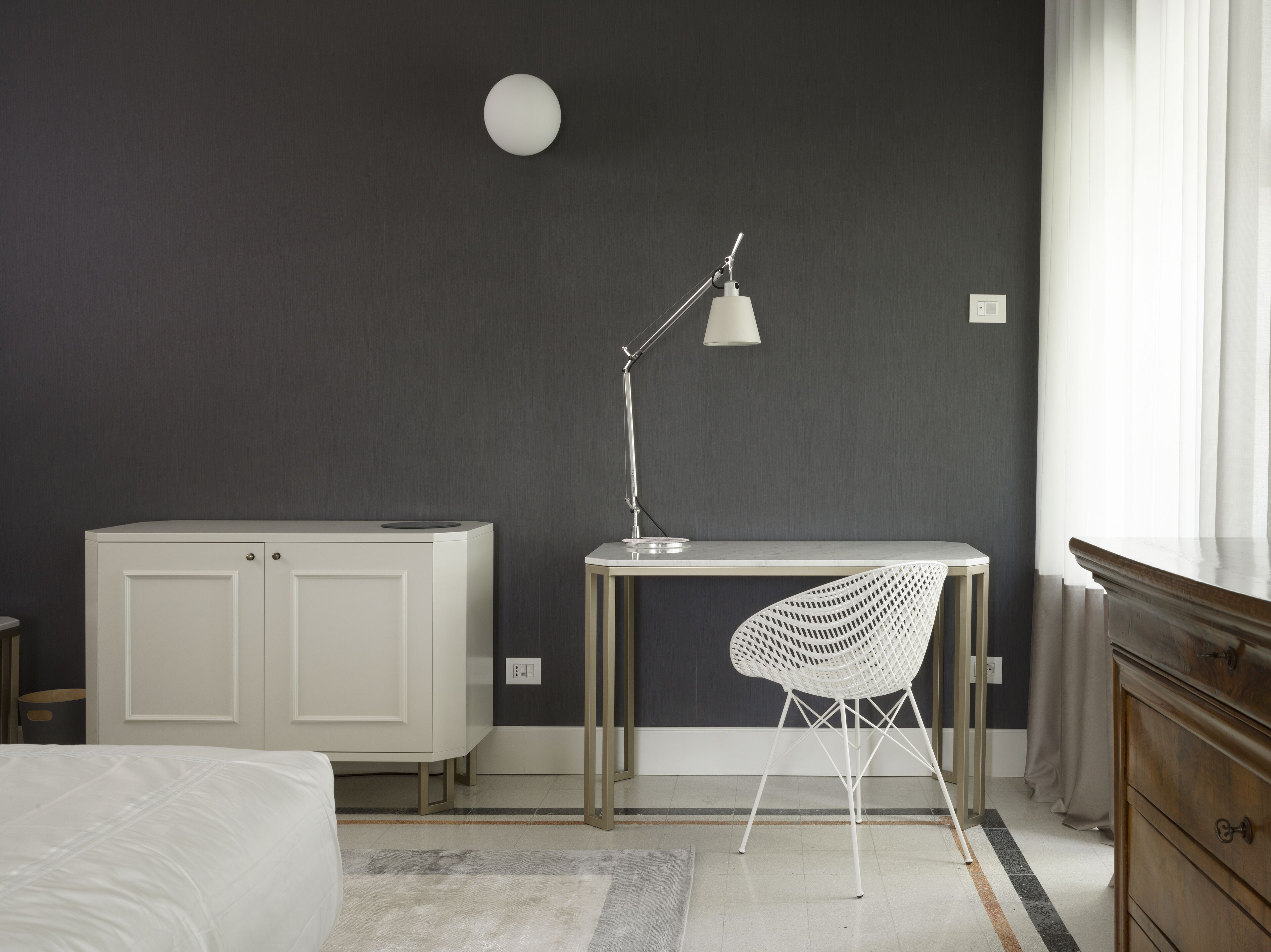 Un dormitorio con cama, escritorio, silla, armario y lámpara.