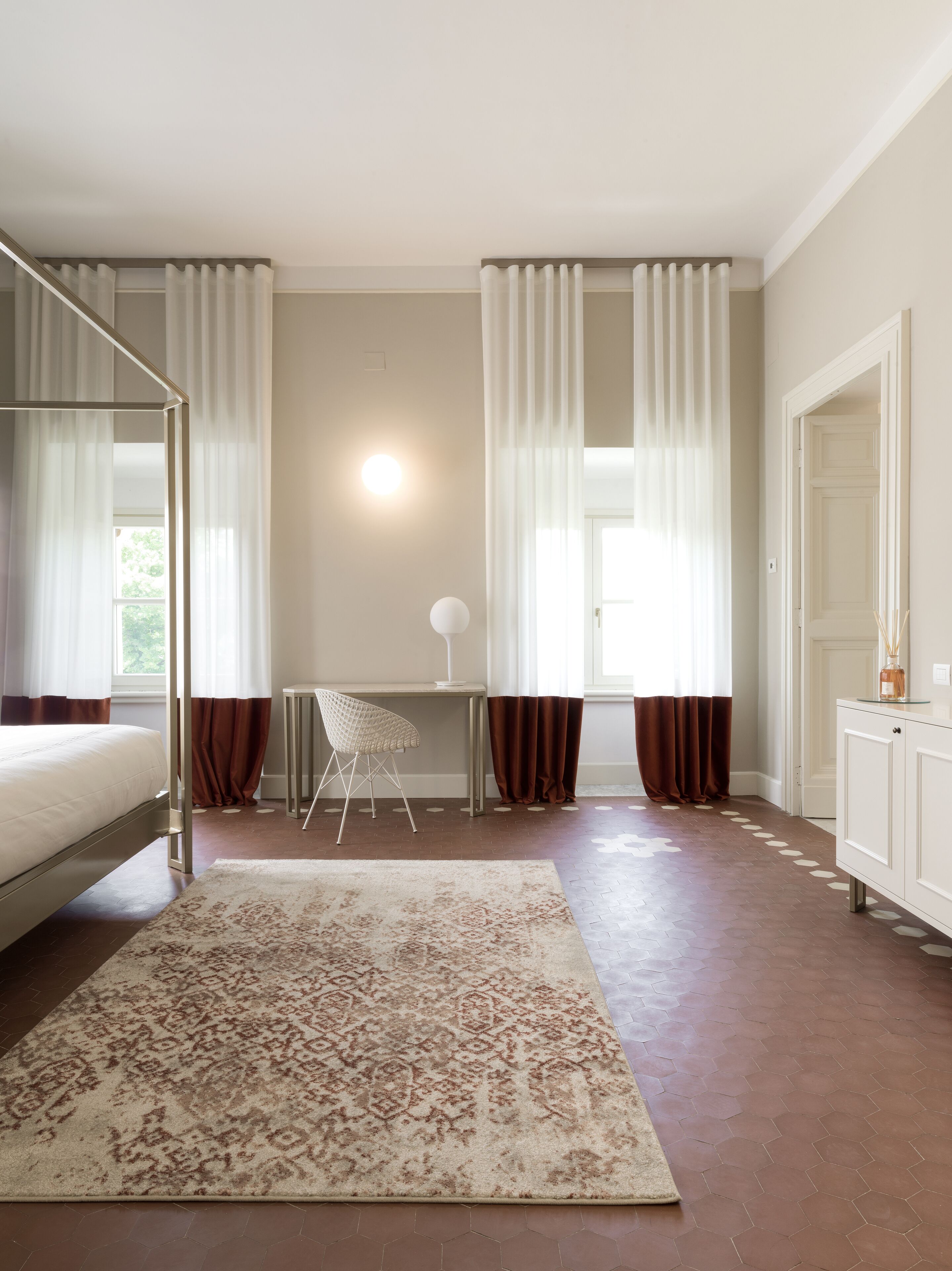 Um quarto com cama, escrivaninha, cadeira, tapete e guarda-roupa.