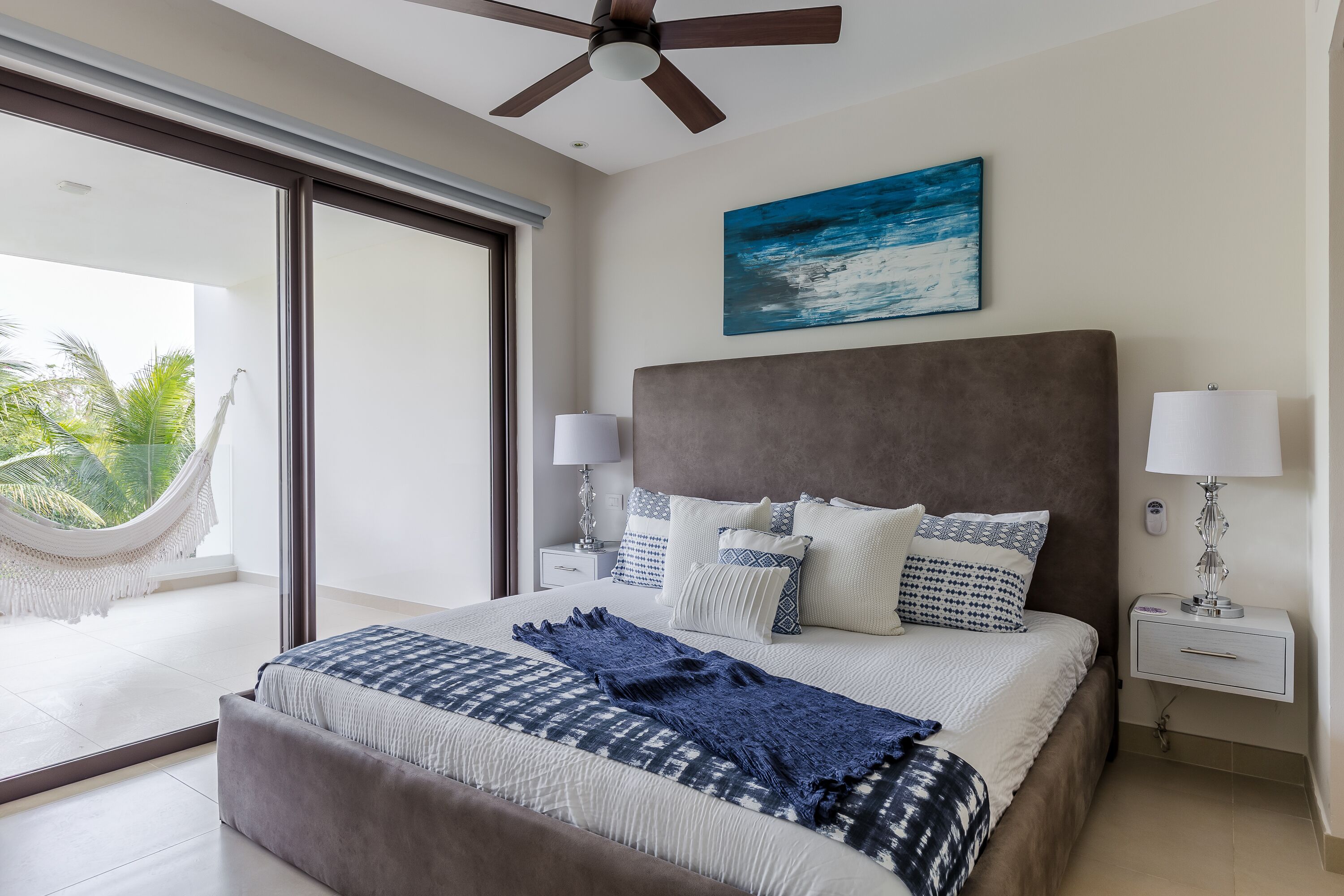Ein Schlafzimmer mit einem großen Bett, einer Hängematte, einem Deckenventilator und Blick ins Freie.