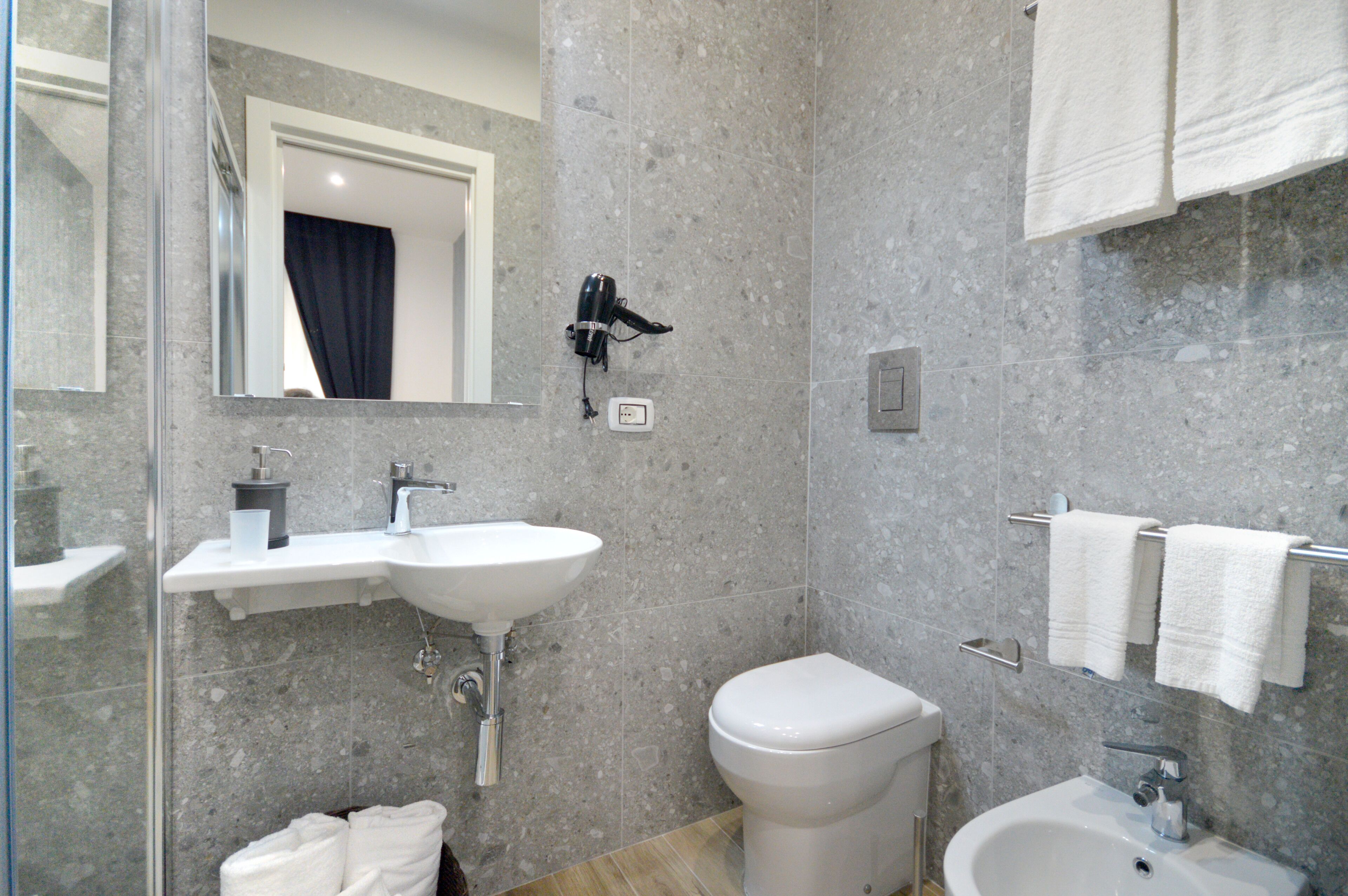 A bathroom with a sink, toilet, and a shower area.