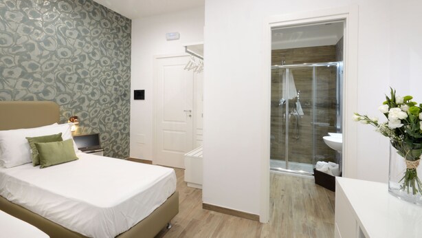 Une chambre d’hôtel comprenant un lit, un bureau avec une lampe, un espace douche et une salle de bain avec un lavabo et des toilettes.