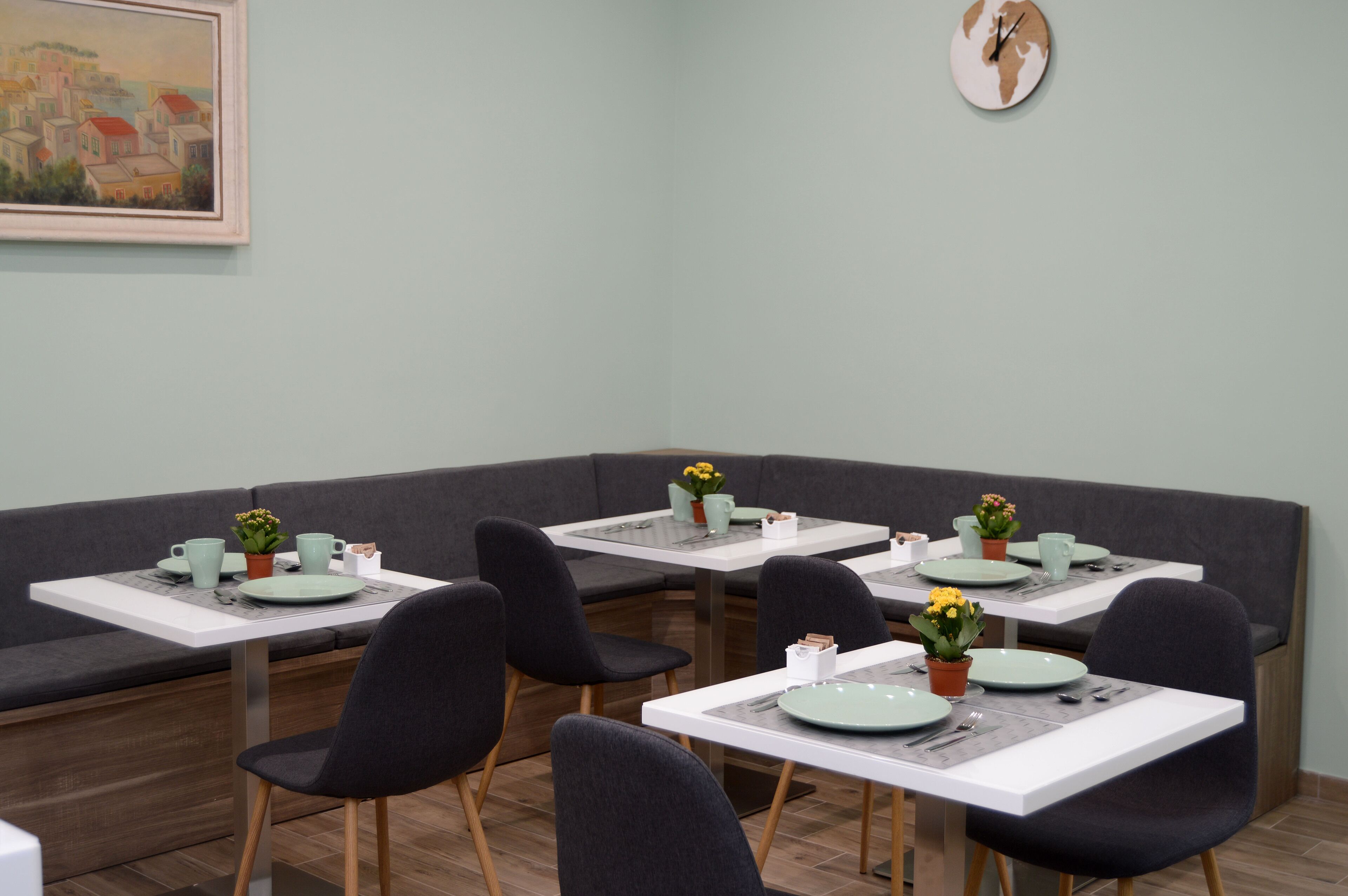 A dining area with booths and tables, each set with plates, cutlery, and small potted plants.