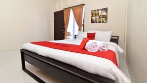 A modern hotel room with a large bed, a dark wooden headboard, and a red blanket.
