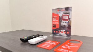 A hotel reception desk with a RedDoor2 sign, a remote control, a white device, and red promotional cards.
