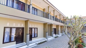 A multi-story hotel with balconies, large doors, and a tiled walkway.