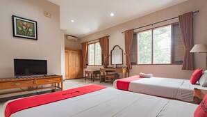 A hotel room with two beds, a desk, a chair, a television, and a window with curtains.