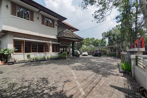 A paved driveway leading to a building with multiple windows and a tiled roof. - RedDoorz near Institut Teknologi Bandung 2 (Bandung)
