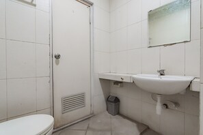 A small, white bathroom with a toilet, a sink, and a mirror. - RedDoorz near Institut Teknologi Bandung 2 (Bandung)