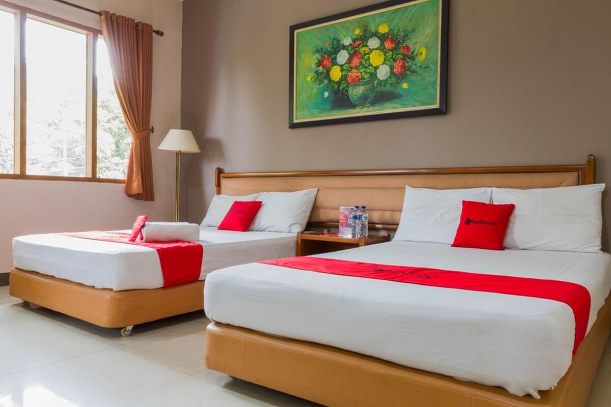 Ein Hotelzimmer mit zwei Betten, einem Bild an der Wand und einem Fenster mit Vorhängen.