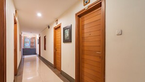 A hallway with wooden doors, a tiled floor, and a framed picture on the wall.