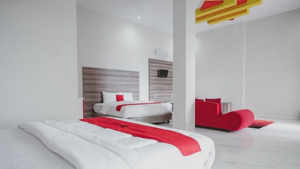 Una camera d'albergo moderna con un letto grande, una parete decorata di rosso e un design minimalista.