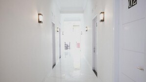 Un corridoio luminoso e bianco con porte numerate 02 e 03, e luci a parete.