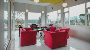 Un'ampia stanza con grandi finestre, divani rossi e soffitto giallo.