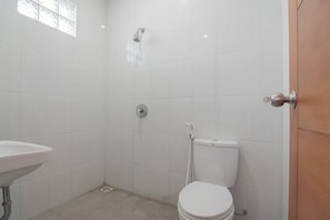A small, white-walled bathroom with a toilet, a shower, and a sink. - RedDoorz Syariah @ Sarongge Cianjur (Cipanas)