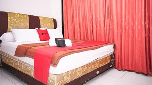 A neatly made bed with a red blanket, white pillows, and a red pillow. - RedDoorz near Palembang Square Mall 2 (Palembang)