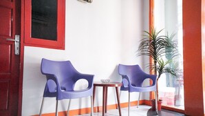 A room with two purple chairs, a small wooden table, and a potted plant. - RedDoorz near Palembang Square Mall 2 (Palembang)