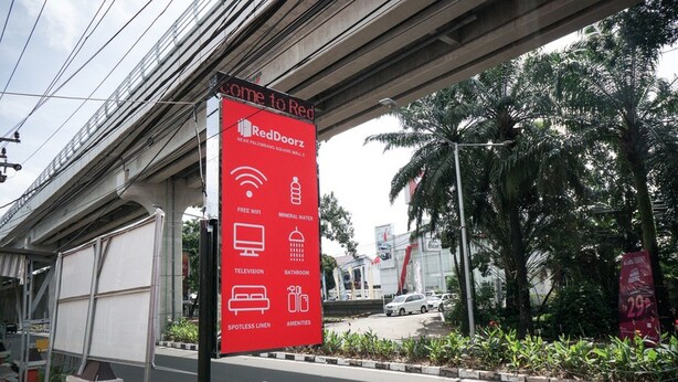 A RedDoorz signboard advertising amenities like free WiFi, mineral water, television, bathroom, spotlessness, and amenities. - RedDoorz near Palembang Square Mall 2 (Palembang)