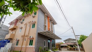 A multi-story residential building with a modern design, featuring a mix of stone and plaster exterior, multiple balconies, and air conditioning units. - RedDoorz Syariah @ Panglima Polem Aceh (Banda Aceh)