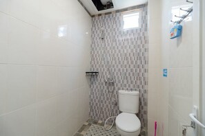 A small, tiled bathroom with a shower, toilet, and a window. - RedDoorz Syariah @ Panglima Polem Aceh (Banda Aceh)