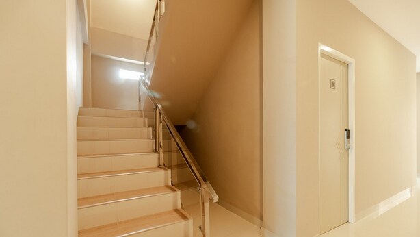 A staircase with wooden steps and a glass railing leading to a door. - RedDoorz Syariah @ Panglima Polem Aceh (Banda Aceh)