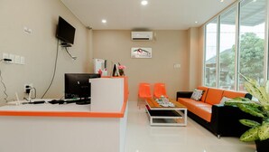 A modern hotel lobby with a reception desk, seating area, and large windows. - RedDoorz Syariah @ Panglima Polem Aceh (Banda Aceh)