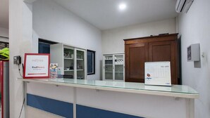 A reception area with a glass counter, a RedDoorz sign, a calendar, and wooden cabinets.