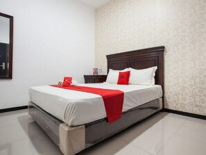 A neatly made bed with a red accent, a wooden headboard, and a patterned wall. - RedDoorz near Taman Krida Budaya Malang (Malang)