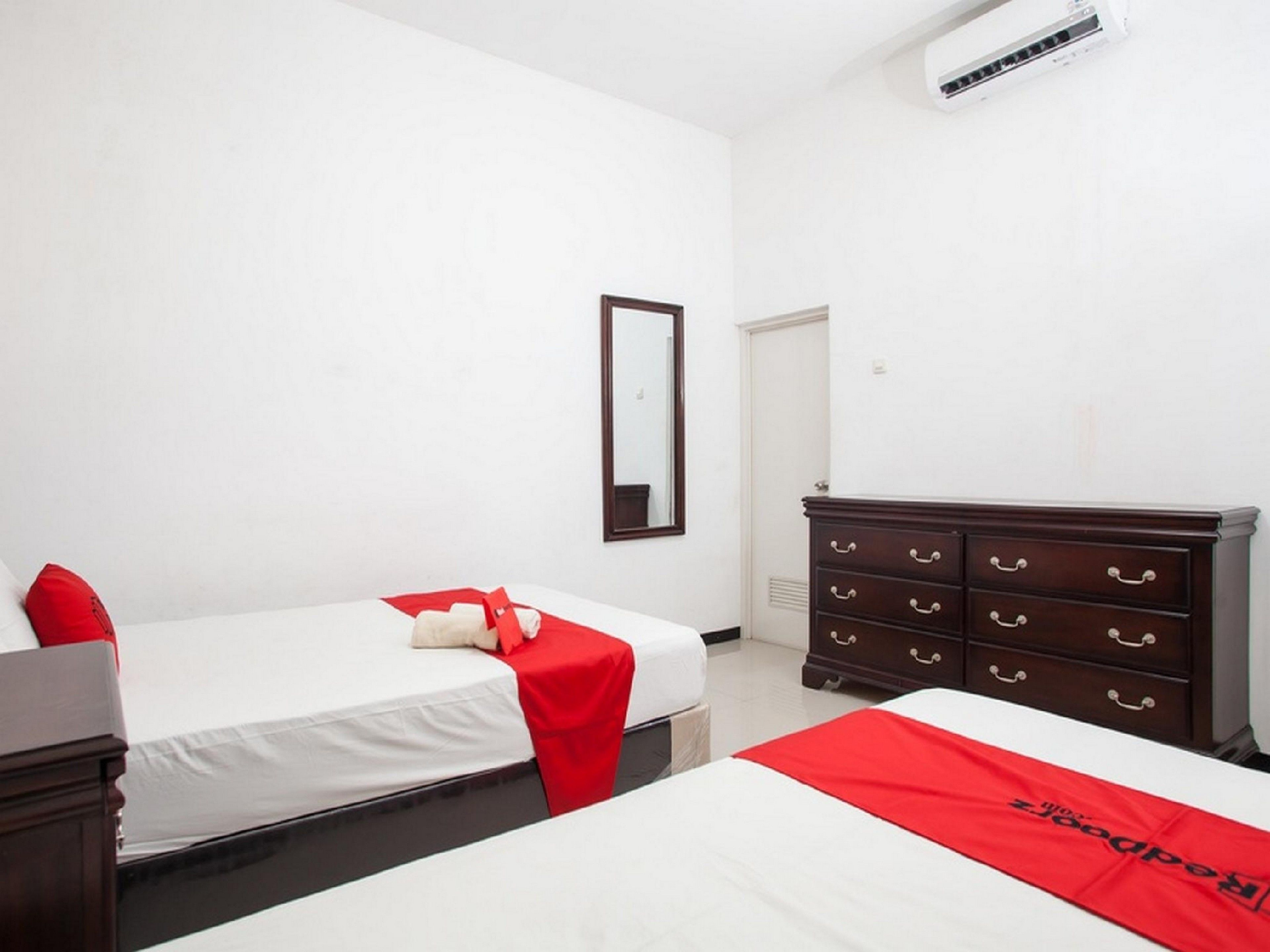 A hotel room with two beds, a dresser, a mirror, and an air conditioning unit.