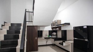 A modern kitchen with black appliances, a wooden door, and a staircase.