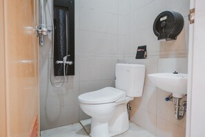 A compact bathroom with a white toilet, a shower, and a sink.