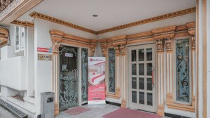 Ein Hotel Eingang mit einer Rezeption, einem RedDoorz Schild und einer Tür mit Glasfenster.