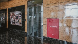 A lobby with a glass elevator, a red hydrant box, and a large poster on the wall. - RedDoorz Apartment @ Saladin Mansion Margonda (Depok)