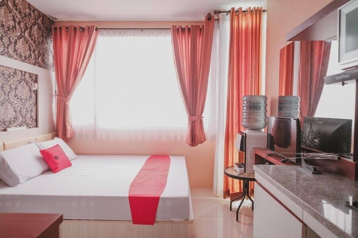 Ein Hotelzimmer mit Bett, Schreibtisch, Fernseher und einem Fenster mit Vorhängen.