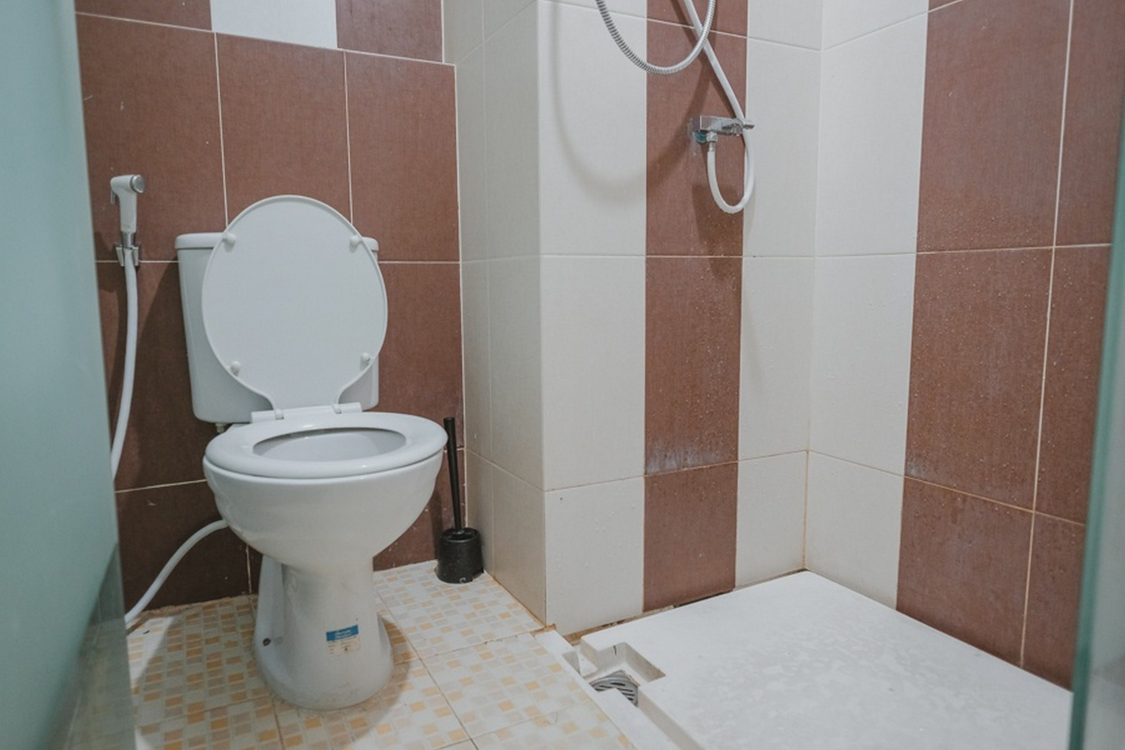 A bathroom with a toilet, shower, and tiled floor.