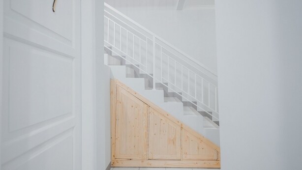 Een trap met een houten leuning en een witte muur.