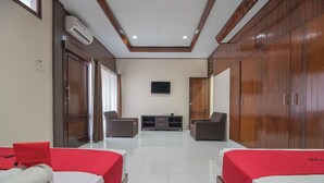 Una habitación de hotel con dos camas, televisión, sofá y mueble para televisión.