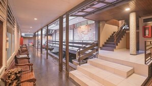 Un vestíbulo amplio con una larga zona de asientos en banco, una escalera y vistas al exterior.