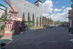 Welcome to our hotel, where a paved driveway leads to a convenient parking area and a beautifully landscaped entrance.