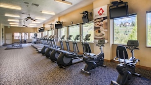 A gym with multiple treadmills, stationary bikes, and a ceiling fan.