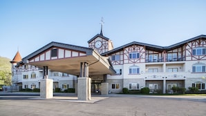 A large hotel with a covered entrance, multiple balconies, and a clock tower.