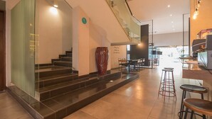 A modern hotel lobby with a staircase, a large vase, and a bar area. - RedDoorz Plus @ Cipaganti Street 3 (Bandung)
