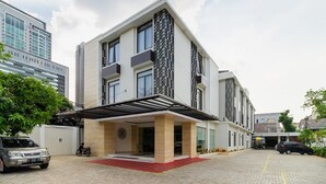 Een modern meerlaags gebouw met een overdekte ingang en een verharde oprit.