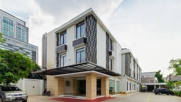 A modern multi-story building with a covered entrance and a paved driveway.