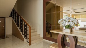 Een modern interieur met een houten trap, een glazen deur en een houten tafel met een bloevas.