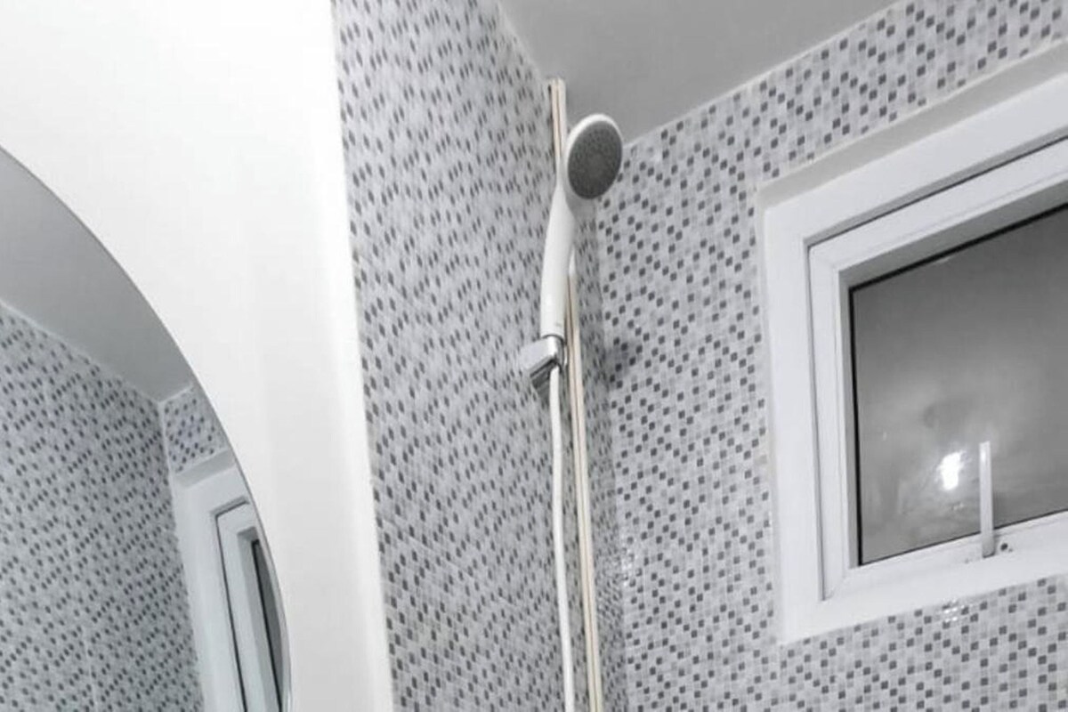 Une douche équipée d’un pommeau de douche à main et d’une fenêtre donnant sur l’extérieur.