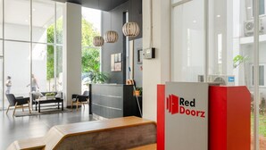 Zona de recepció de Red Doorz amb un disseny modern, que inclou una banca de fusta, grans finestres i un taulell de recepció.