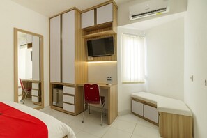 A bedroom with a bed, a desk, a chair, a TV, and a small bedside table.