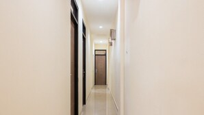 A narrow, well-lit hallway with a door at the end. - RedDoorz @ Tebet Barat 2 (Jakarta)